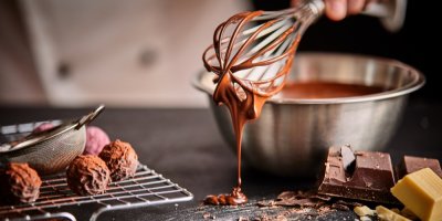 Kuchař zdobí rozpuštěnou čokoládou pralinky