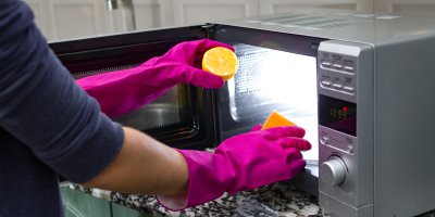 Člověk čistí mikrovlnku pomocí houbičky a citronové šťávy