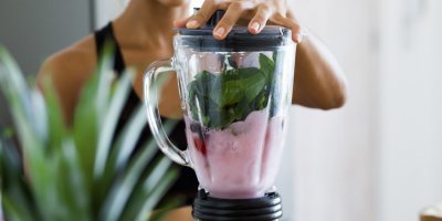 Žena mixuje smoothie z lesních plodů a špenátu v mixéru