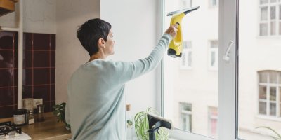 Žena umývá okna stěrkou