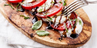 Salát Caprese na dřevěném prkénku.