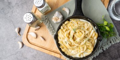 Těstoviny na pánvičce, zalité krémově bílou omáčkou a posypané bylinkami