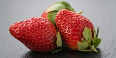 3 jahody na tmavém pozadí