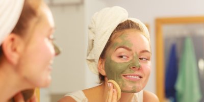 Žena si smývá pleťovou masku u zrcadla