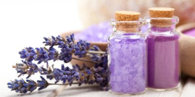 Dvě lahvičky s levandulovou solí a kytice sušených levandulí v pozadí