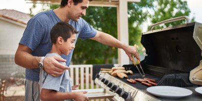 Otec učí syna, jak grilovat párky
