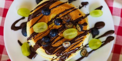 Lívance na talíři, polité čokoládou a zdobené zrníčky vinné révy