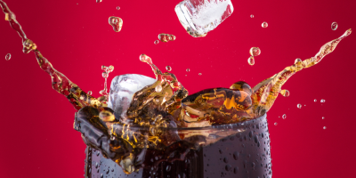 Sklenice coly, do které jsou vhazovány kostky ledu