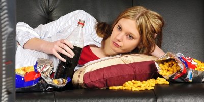 Žena na gauči s nezdravým jídlem