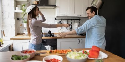 Mladý pár proti sobě v kuchyni pro zábavu bojuje naběračkami