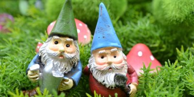 Pohádkoví zahradní trpaslíci v kouzelném lese se zeleným mechem a houbami