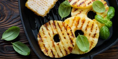 Grilovaný ananas na grilovací pánvi, bazalka a kousek medu