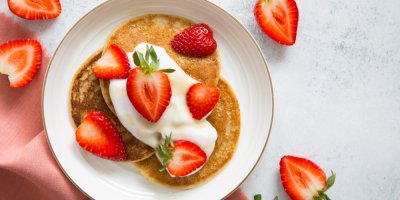 Talíř vegetariánských palačinek s čerstvými jahodami a šlehačkou na bílém talíří