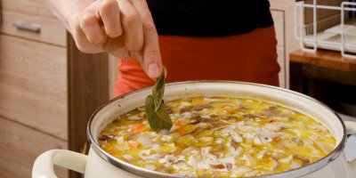 Člověk přidává bobkový list do polévky