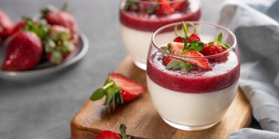 Dezert panna cotta ve skleničce na prkénku, kolem jahody