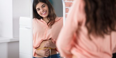 Žena si měří pas před zrcadlem 