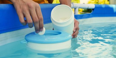 Muž dává do bazénu chlorovou tabletu