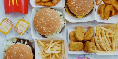 Směs produktů z fastfoodu McDonalds's – hamburgery, hranolky a americké brambory, kuřecí nugetky a omáčky