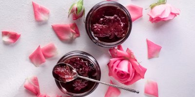 Marmeláda ve sklenicích na stole posypaném květy růží
