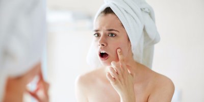 Žena s umytými vlasy, která si před zrcadlem překvapeně prohlíží svoji tvář