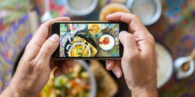 Člověk fotografující mobilním telefonem stůl s jídlem