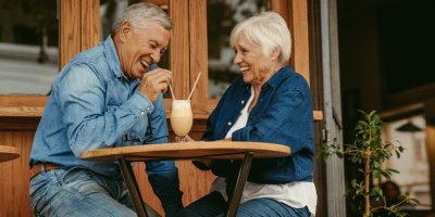 Starší pár popíjející kávu na zahrádce kavárny