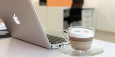 Notebook od značky Apple a šálek kávy na stole