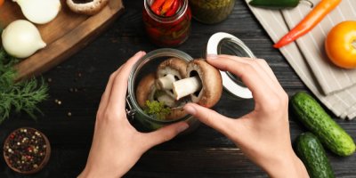 Člověk skládající houby do sklenice