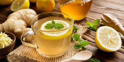 Zázvor a plátky citronu ležící vedle hrnku se zázvorovým čajem