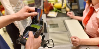 Muž platí kreditní kartou na pokladně v supermarketu