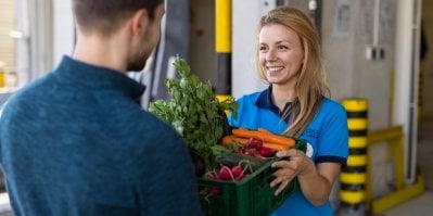 Prodavačka z prodejny Tesco předává bedýnku se zeleninou muži
