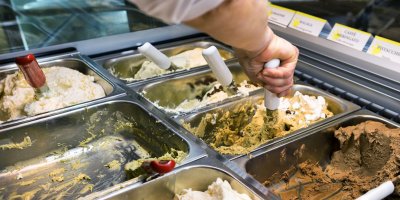 Mužská ruka nabírá kopečkovou zmrzlinu z vaničky