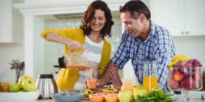 Žena s mužem si ke snídani připravují v mixéru ovocné smoothie