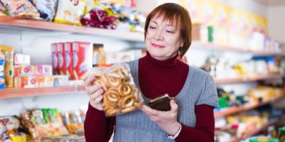 Žena si v obchodě čte složení balení preclíků.