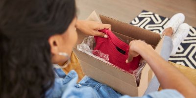 Žena vybaluje online objednávku oblečení z krabice