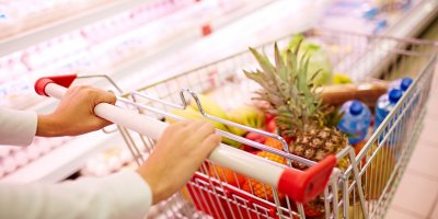 Nákupní košík vedle regálu v supermarketu