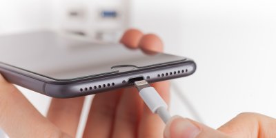 Osoba zapojuje nabíječku do telefonu iPhone