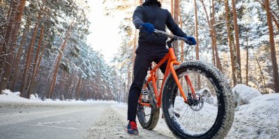 Cyklista stojí u krajnice v zimním lese