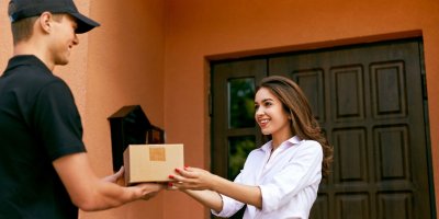 Kurýr předává zákaznici balíček v kartonové krabici