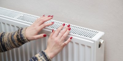 Žena šahá rukama na radiátor