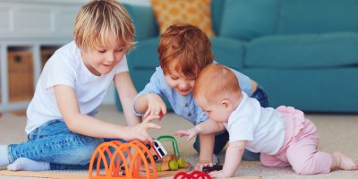Trojice sourozenců si hraje se stavebnicí a autíčky