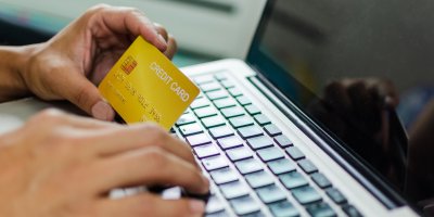 Muž drží kreditní kartu nad notebookem