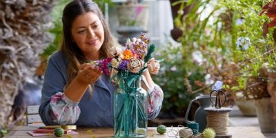 Žena si prohlíží květiny z LEGO stavebnice ve váze