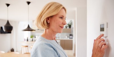 Žena nastavuje termostat na zdi