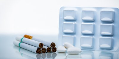 Nikotinové žvýkačky vedle hromádky cigaret