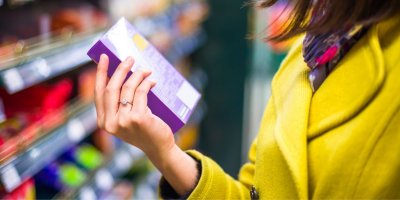 Váhající žena studuje váhu a složení potravin na obale