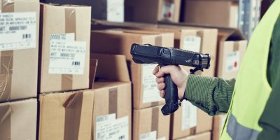 Muž skenuje balíčky v logistickém centru