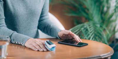 Muž se dívá na displej smartphonu zatímco používá oxymetr