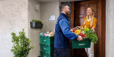 Kurýr předává nákup ženě před domem 