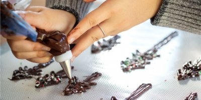 Ruce ženy tvoří stromečky z čokolády